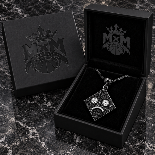 MxM Black diamond-eye sad face pendant concept, matching MxM-logo luxury box on black marble tabletop.