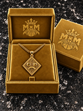 Gold MxM sad-face necklace in matching velvet box with crests inside and outside