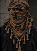 MxM tan and black spiderweb keffiyeh on a model with prominent spider face motif, crowned MxM basketball logo and thin knotted tassels. Digital design preview, not a manufactured sample photo.
