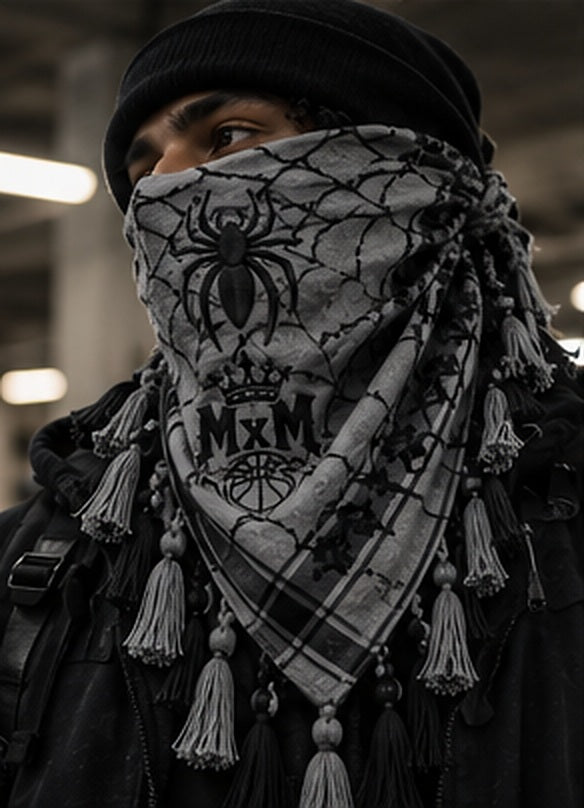 MxM spiderweb keffiyeh black white model styling concept: face spider, crowned MxM basketball logo, triangular web pattern and knotted tassel fringe. Digitally rendered, not a manufactured sample photo.