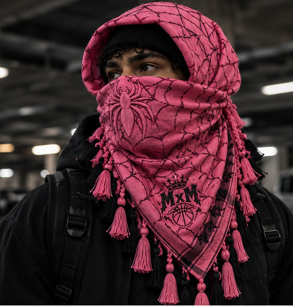 MxM spiderweb keffiyeh pink hero model styling concept: face spider, crowned MxM basketball logo, triangular web pattern and knotted tassel fringe. Digitally rendered, not a manufactured sample photo.