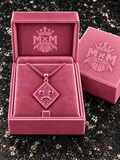 Pink MxM sad-face necklace in matching velvet box with crests inside and outside