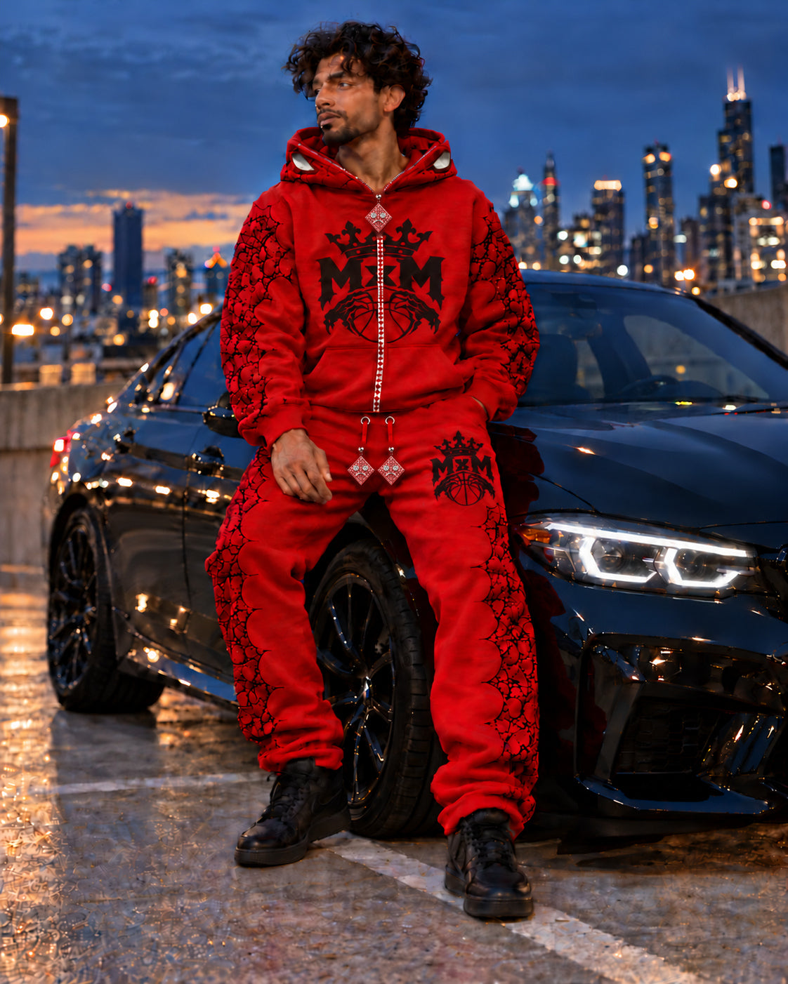 Model wearing MxM red tracksuit with the same fixed sad-face rhinestone charm design used across all colorways.