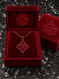 Red MxM sad-face necklace in matching velvet box with crests inside and outside